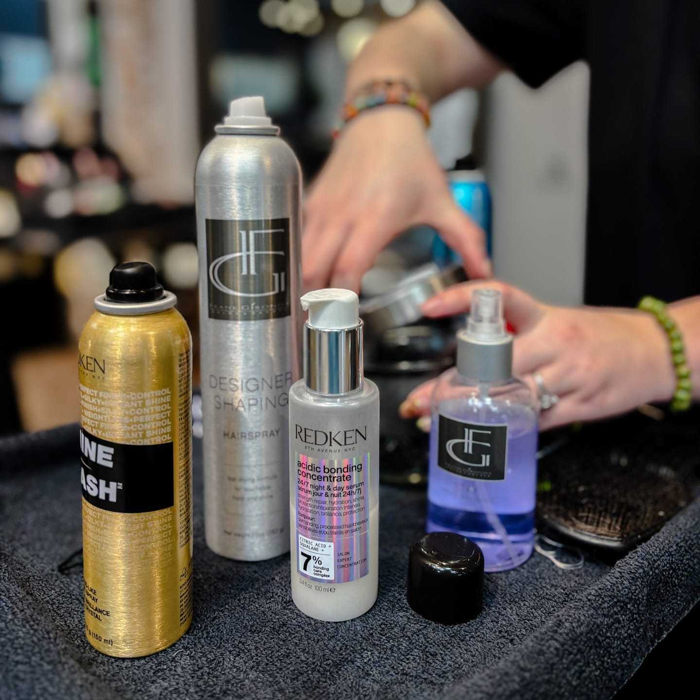 Haircare products on a salon counter with stylist's hands in the background.