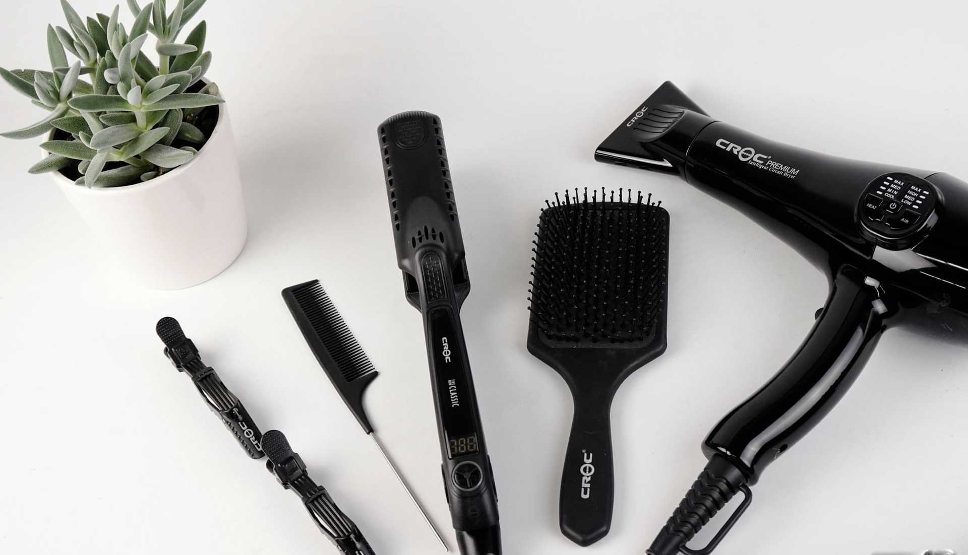 Hair styling tools and a potted plant on a white surface.