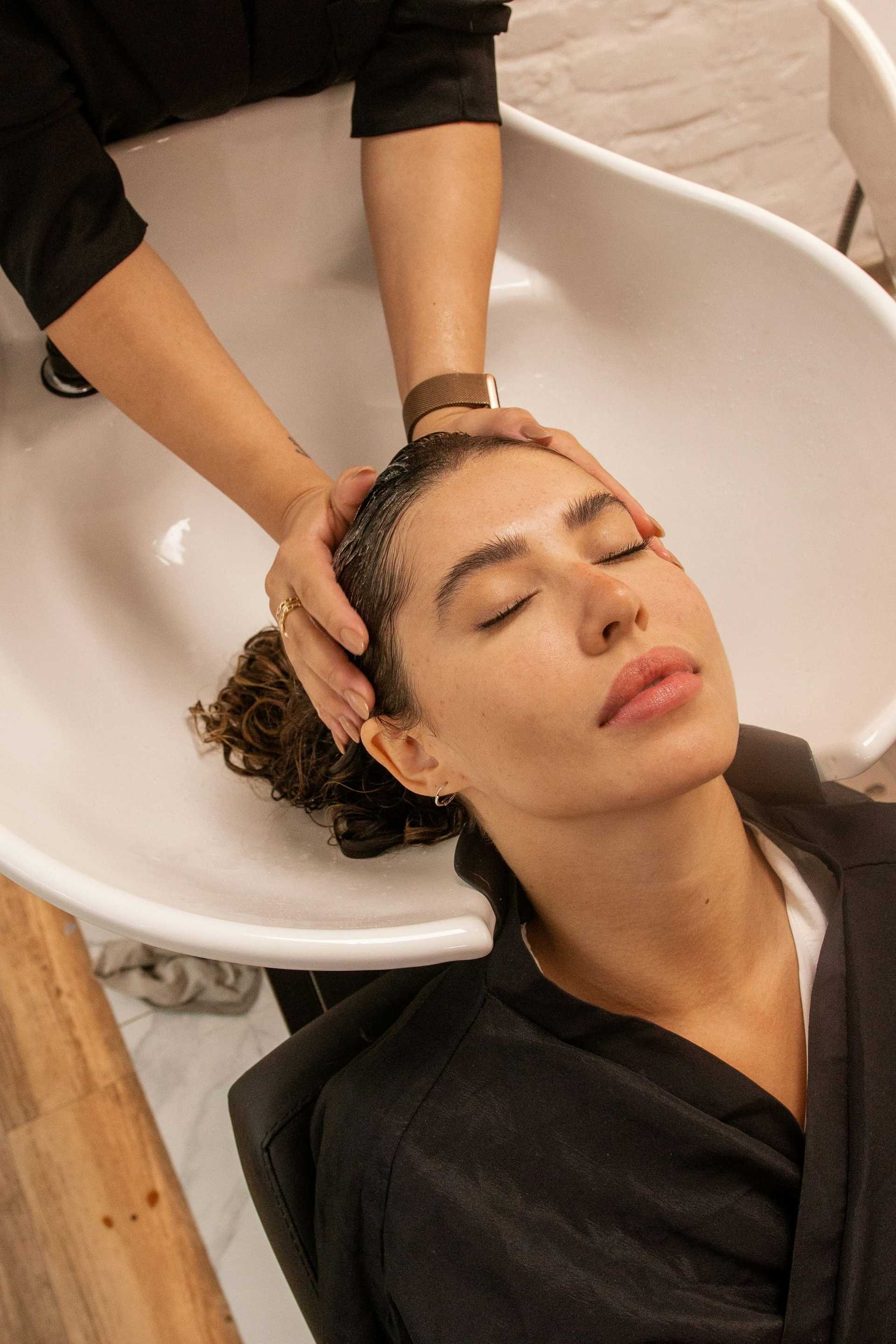 Person relaxing during a hair wash at a salon sink.
